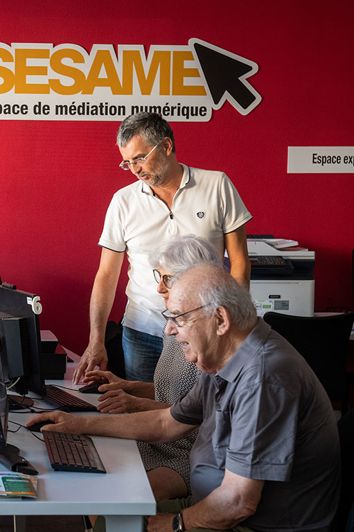 Trois personnes devant des ordinateurs à l'Espace Sésame (c) C. Goussard