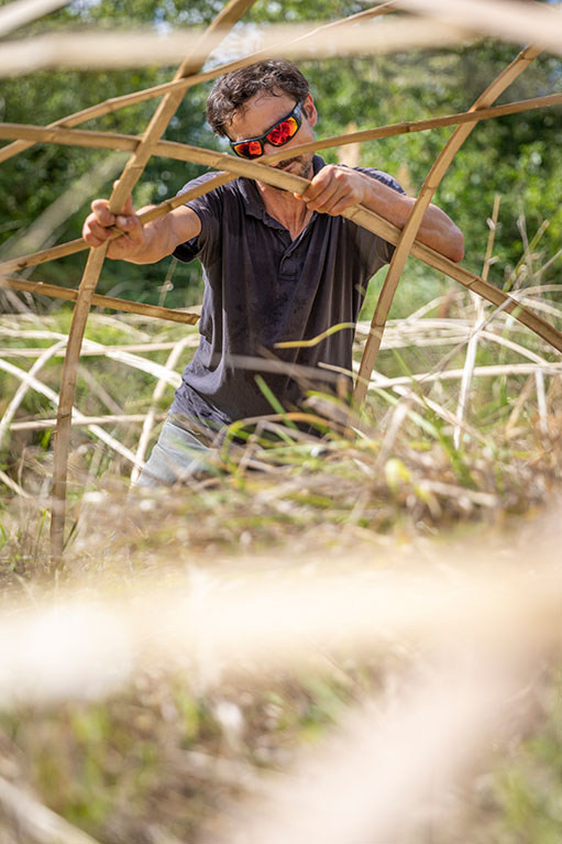 Homme assemble une serre en bambou (c) A Sibelait